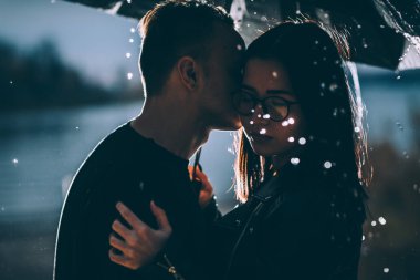 Karanlık bir şemsiye altında duran genç bir çift..