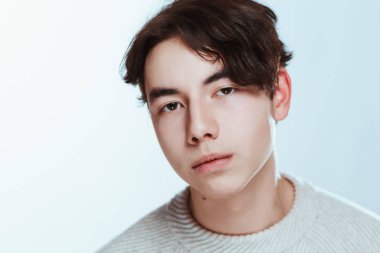 Stüdyo portre genç adam beyaz arka planda gri süveterli.