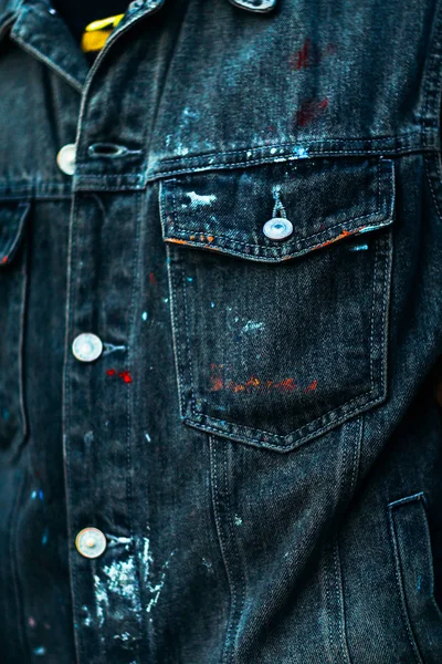 Denim jacket in paint stains close up.