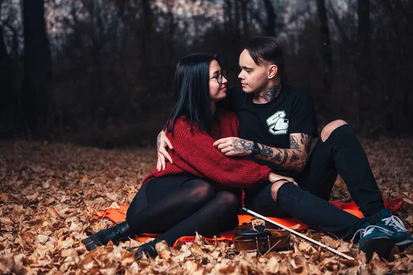 若い男と若い女は秋の森で格子縞に座っています — ストック写真