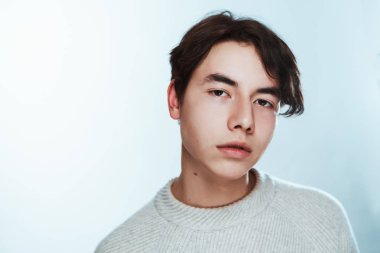 Stüdyo portre genç adam beyaz arka planda gri süveterli.