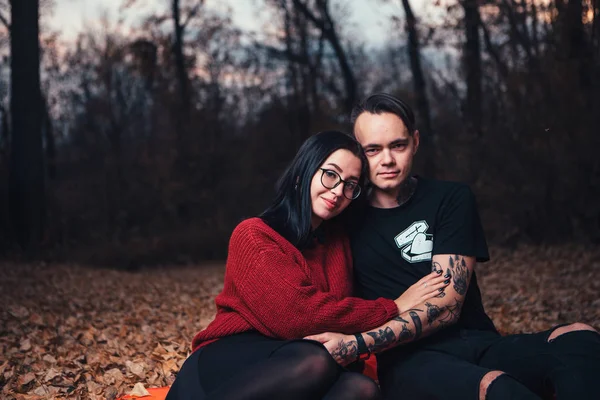 若い男と若い女は秋の森で格子縞に座っています — ストック写真