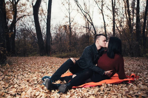 年轻的男人和年轻的女人坐在一个格子在秋天的森林 — 图库照片