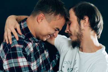 Koyu bir arka planda sarılan iki adam..