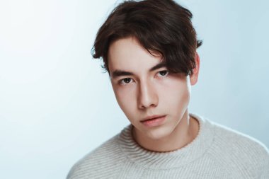 Stüdyo portre genç adam beyaz arka planda gri süveterli.