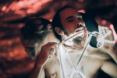 Koyu renk arka planda sarılan iki adam ve Strip Light bandı..