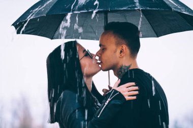 Karanlık bir şemsiye altında duran genç bir çift.