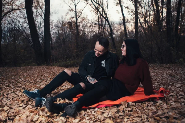 Young man and young woman are sitting on a plaid in an autumn fo — Stock Photo, Image