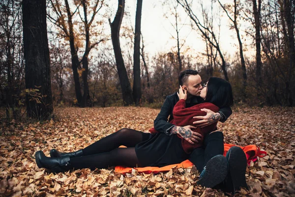 Young man and young woman are sitting on a plaid in an autumn fo — Stock Photo, Image
