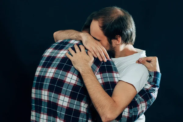 two guys hugging on a dark background
