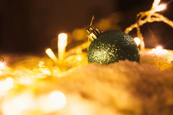 Bola de Natal azul e guirlanda luminosa na neve — Fotografia de Stock