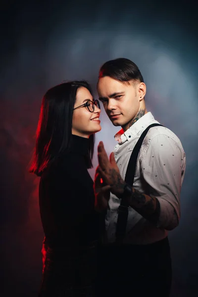 Paar in modischer Kleidung auf dunklem, rauchigen Hintergrund — Stockfoto