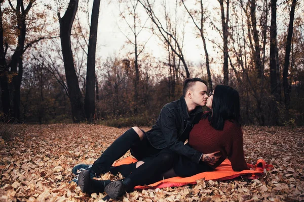 Hombre joven y mujer joven están sentados en un cuadros en un otoño fo —  Fotos de Stock