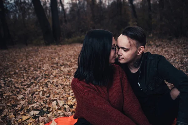 Ein junger Mann und eine junge Frau sitzen auf einem Karo in einem Herbstkleid. — Stockfoto