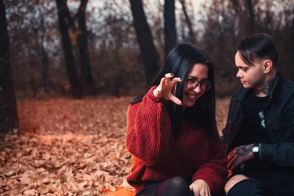 Jeune homme et jeune femme sont assis sur un plaid dans un automne fo — Photo