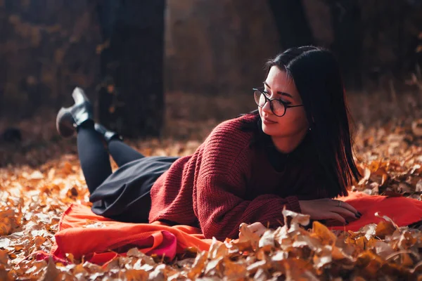 Ragazza sdraiata sul plaid nella foresta autunnale, sfondo naturale — Foto Stock