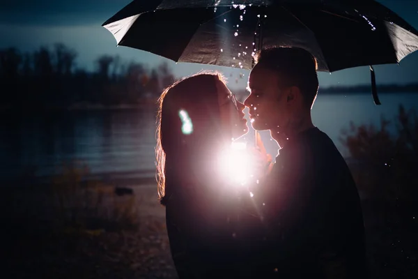 Jovem homem e mulher sob um guarda-chuva e chuva — Fotografia de Stock