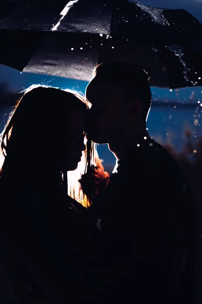 Jovem homem e mulher sob um guarda-chuva e chuva — Fotografia de Stock