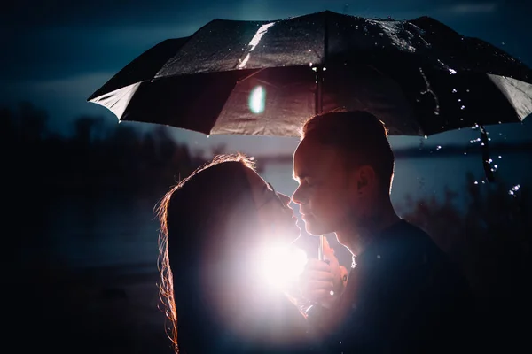 Jovem homem e mulher sob um guarda-chuva e chuva — Fotografia de Stock