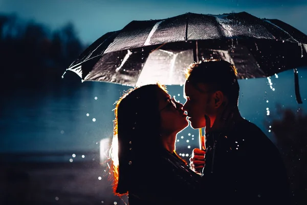 Giovane uomo e donna sotto un ombrello e pioggia — Foto Stock