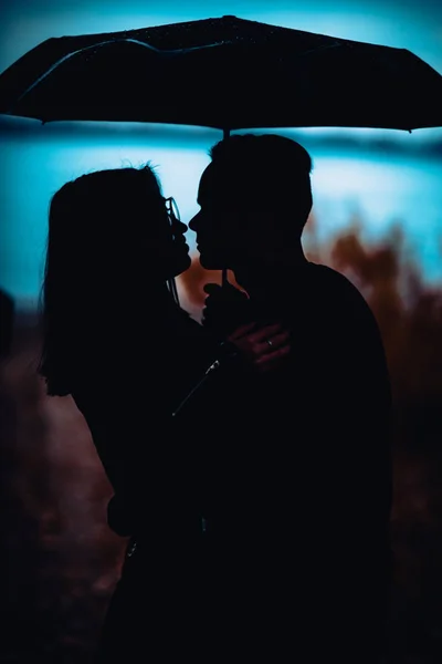 Joven hombre y mujer bajo un paraguas y lluvia — Foto de Stock