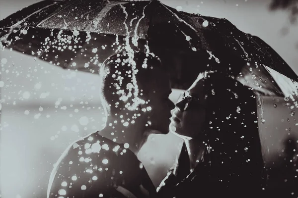 Preto branco foto jovem casal de pé sob um guarda-chuva escuro — Fotografia de Stock