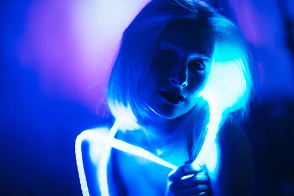 Retrato chica tira cinta de luz sobre fondo de color oscuro — Foto de Stock