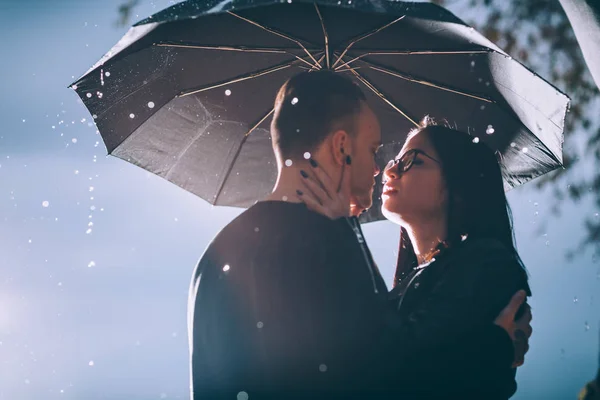 Giovane coppia in piedi sotto un ombrello scuro — Foto Stock