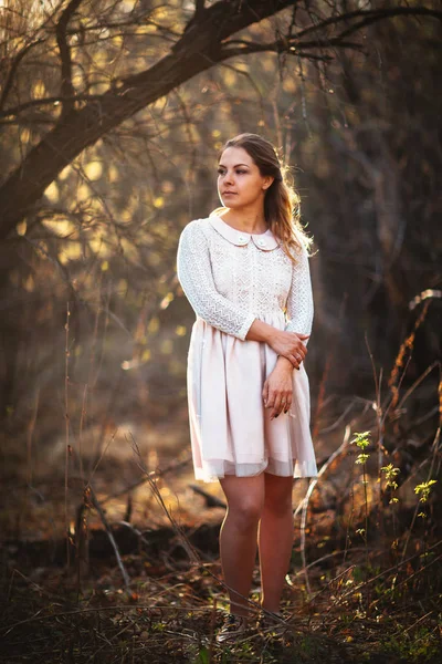 Piękna dziewczyna stoi w polu na tle zachodu słońca — Zdjęcie stockowe