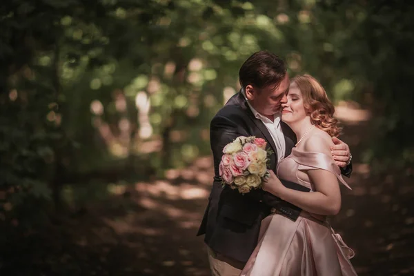 Bruid en bruidegom dansen in het bos achtergrond en zonlicht — Stockfoto