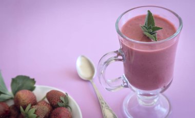 Peçeteye bir bardak çilek güler yüzlü, çilek çilek yanındaki masada. Pembe bir arka plan sundu.