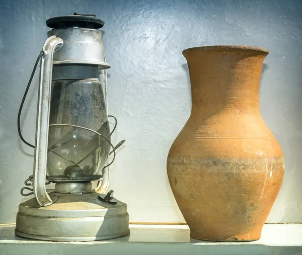 Vintage household items: kerosene lamp and handmade clay jug.