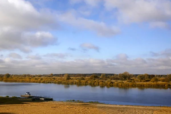 Autumn landscape on the river on a clear autumn day. On the sandy Bank of the river there is a small pier and a boat.