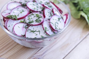 Masada kıyılmış salata turp bir cam kase ve roka çim.