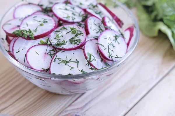 Masada kıyılmış salata turp bir cam kase ve roka çim.