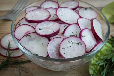 Masada kıyılmış salata turp bir cam kase ve roka çim.