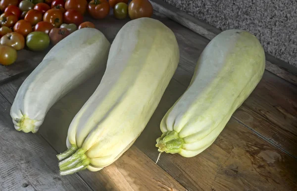 Auf Dem Holztisch Liegen Drei Zucchini Und Tomaten Unterschiedlichen Reifegrades — Stockfoto