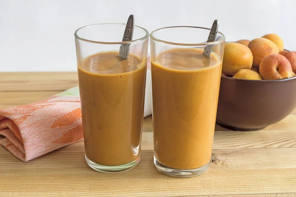 İki cam bardak ile peçeteye masada kayısı güler yüzlü. Yanındaki kayısı cam vazoda.