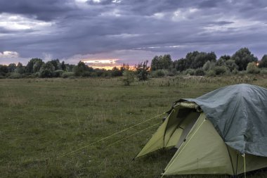 Bir küçük turistik çadır akşam günbatımında forest yakınındaki bir açıklıkta.