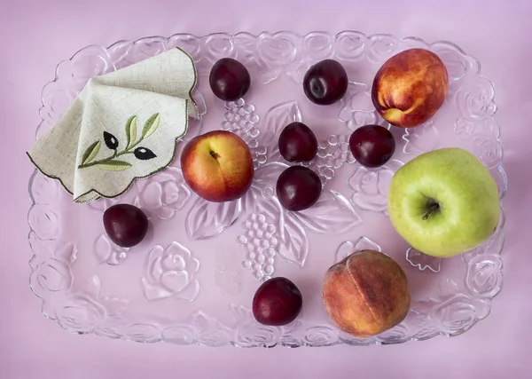 Ένα Δίσκο Ποτήρι Ροζ Φόντο Στο Οποίο Ψέμα Δαμάσκηνα Μήλα — Φωτογραφία Αρχείου