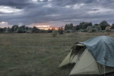 Bir küçük turistik çadır akşam günbatımında forest yakınındaki bir açıklıkta.