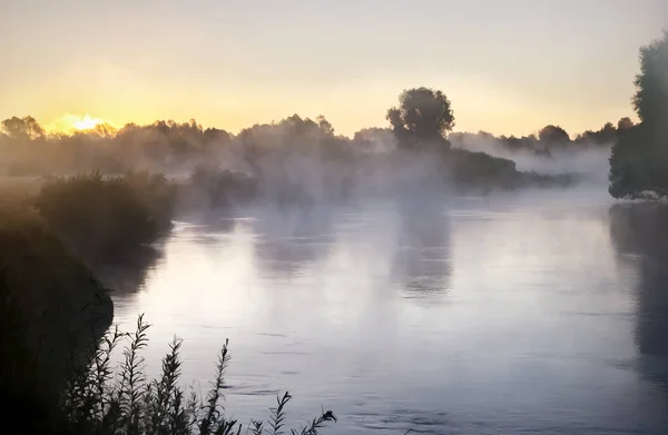 stock image Beautiful calm river with the mist over the surface of the water at dawn by the light of the rising sun.