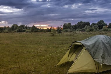 Bir küçük turistik çadır akşam günbatımında forest yakınındaki bir açıklıkta.