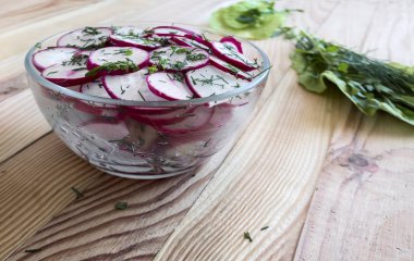 Masada kıyılmış salata turp bir cam kase ve roka çim.