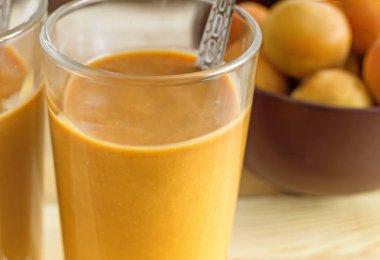 İki cam bardak ile peçeteye masada kayısı güler yüzlü. Yanındaki kayısı cam vazoda.