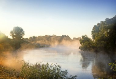 Güzel sakin Nehri üzerinde yükselen güneşin ışığı ile suyun şafakta sis ile.
