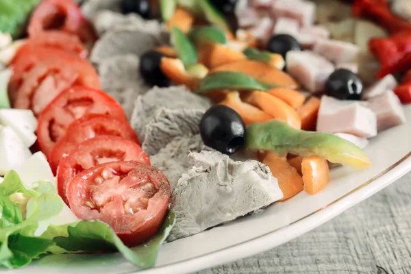 A popular dish of American cuisine - Cobb salad, consisting of greens, eggs, tomatoes, cheese, meat products, stacked in rows on a wide dish and poured sauce.