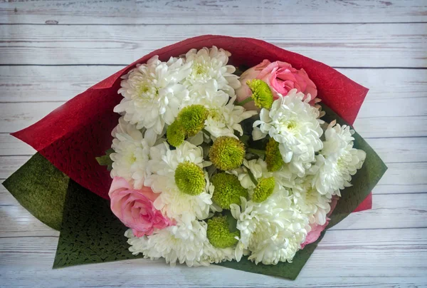 Beautiful bouquet of roses and chrysanthemums in decorative packaging.