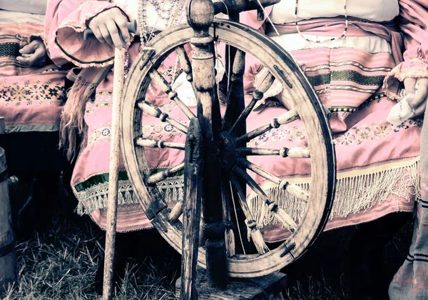 Alte hölzerne Spinnräder und eine Frau in Tracht. — Stockfoto