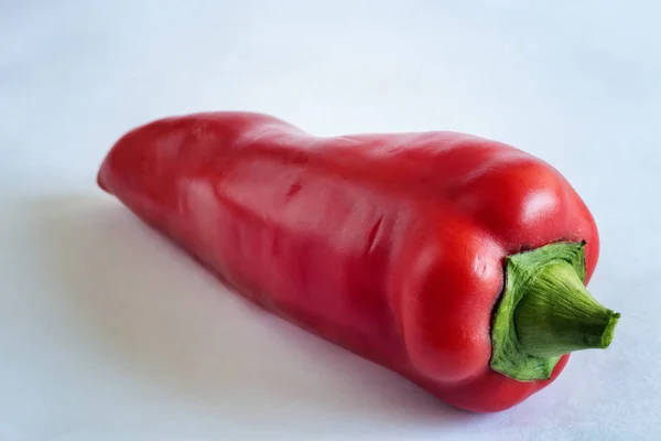 Uma pimenta vermelha em um fundo leve . — Fotografia de Stock